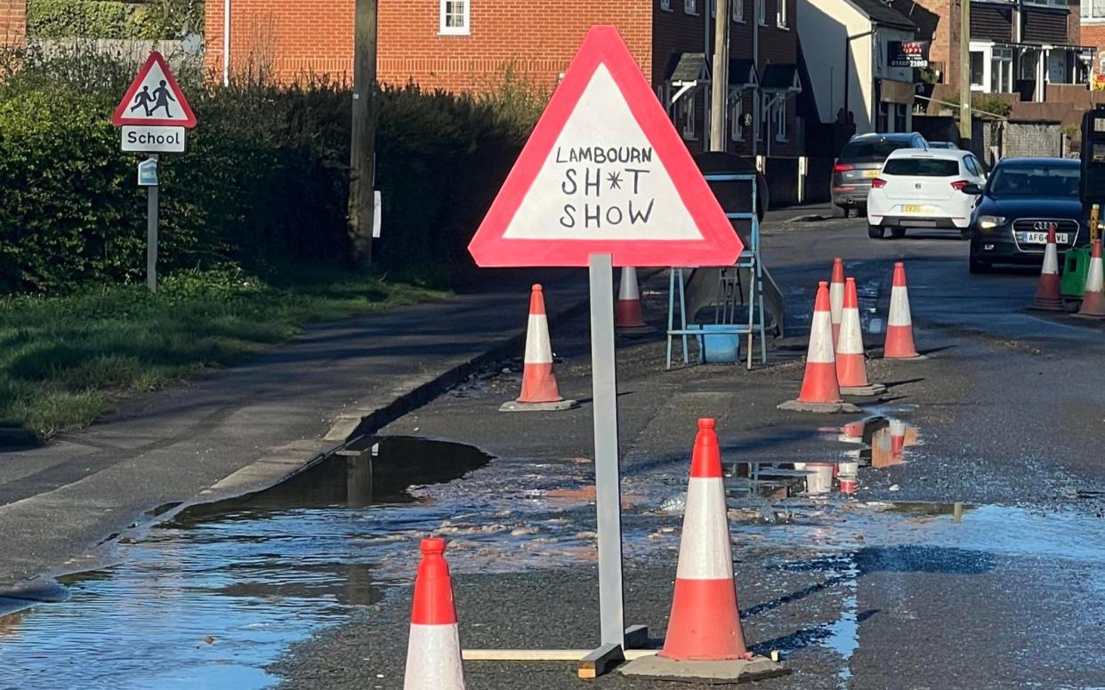 A mock road sign has been positioned along one road with the message 'Lambourne s--- show' written over it