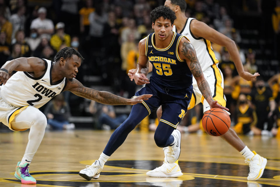 Michigan guard Eli Brooks (55) drives up court ahead of Iowa guard Joe Toussaint (2) during the first half of an NCAA college basketball game, Thursday, Feb. 17, 2022, in Iowa City, Iowa. (AP Photo/Charlie Neibergall)