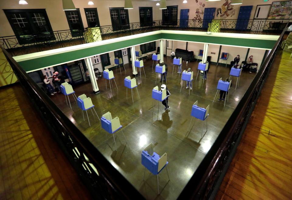 A man wearing a helmet votes in the evening at Bay Beach Amusement Park on Nov. 3, 2020, in Green Bay.