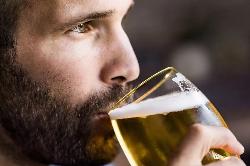 Close up of mid adult man drinking beer in a bar and looking away.