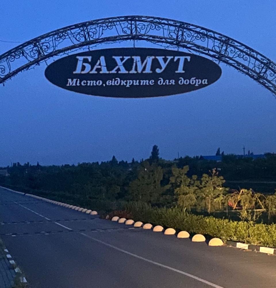 A sign on an arch against a dark sky reads 