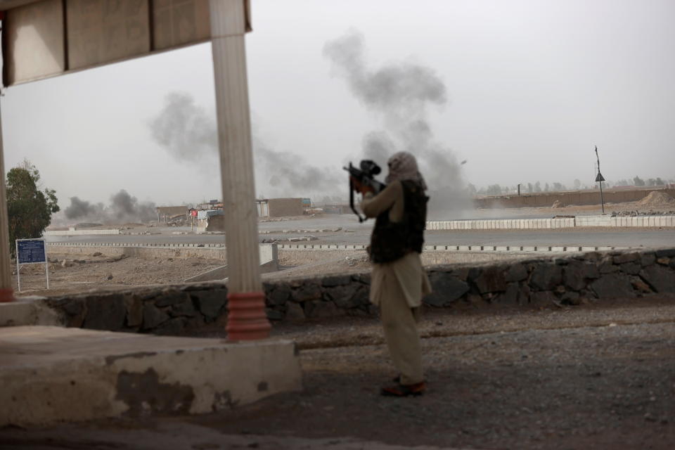 An Afghan soldier holds a gun and looks towards Taliban positions as smoke rises in the distance from clashes on the outskirts of Spin Boldak in Kandahar province, Afghanistan, July 16, 2021. This is one of the last known photographs by Reuters journalist Danish Siddiqui who was killed on the same day. / Credit: DANISH SIDDIQUI / REUTERS