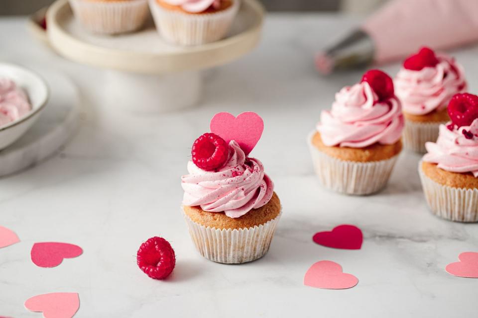 freshly made raspberry cupcakes on kitchen counter delicious looking pink cupcakes with raspberry and paper heart topping