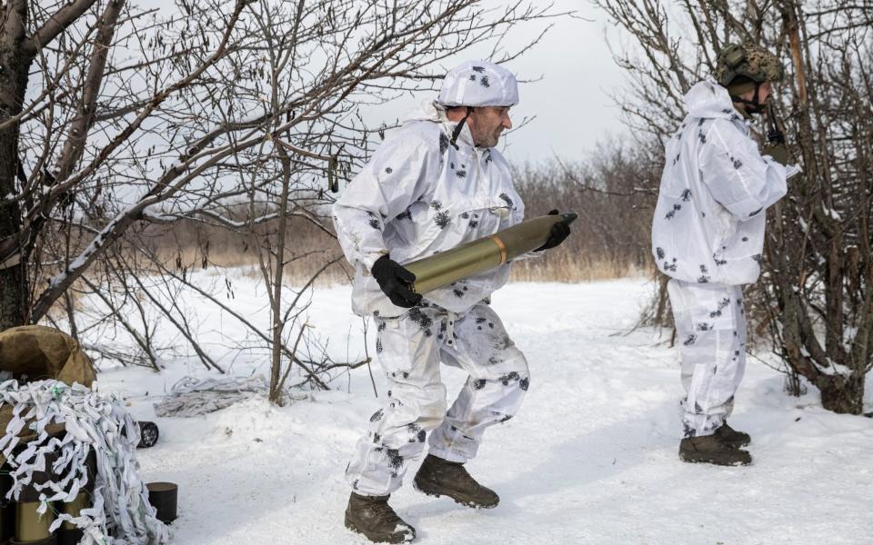 A Ukrainian serviceman of the 80th Air Assault Brigade carries a shell to load into an M119 Howitzer artillery weapon to be fired towards Russian troops