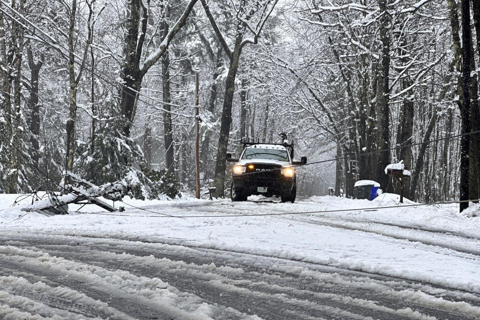 Wires from a fallen utility pole block a snow-covered road, Thursday, April 4, 2024, in Bow, New Hampshire. (AP Photo/Holly Ramer)