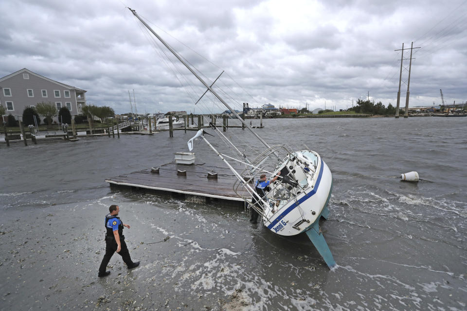 Beaufort Police Officer Curtis Resor, left, and Sgt. Micheal Stepehens check a sailboat for occupants in Beaufort, N.C. after Hurricane Dorian passed the North Carolina coast on Friday, Sept. 6, 2019. Dorian howled over North Carolina's Outer Banks on Friday — a much weaker but still dangerous version of the storm that wreaked havoc in the Bahamas — flooding homes in the low-lying ribbon of islands and throwing a scare into year-round residents who tried to tough it out. (AP Photo/Tom Copeland)