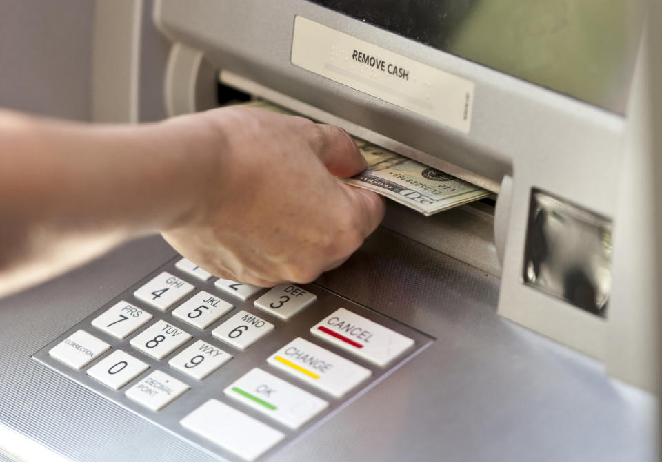 caucasian female hand picking the cash from an ATM