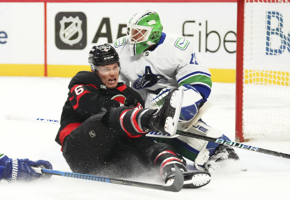 Ottawa Senators defenseman Jakob Chychrun (6) slams into Vancouver Canucks goaltender Casey DeSmith (29) during the first period of an NHL hockey match in Ottawa, Ontario, on Thursday, Nov. 9, 2023. (Sean Kilpatrick/The Canadian Press via AP)