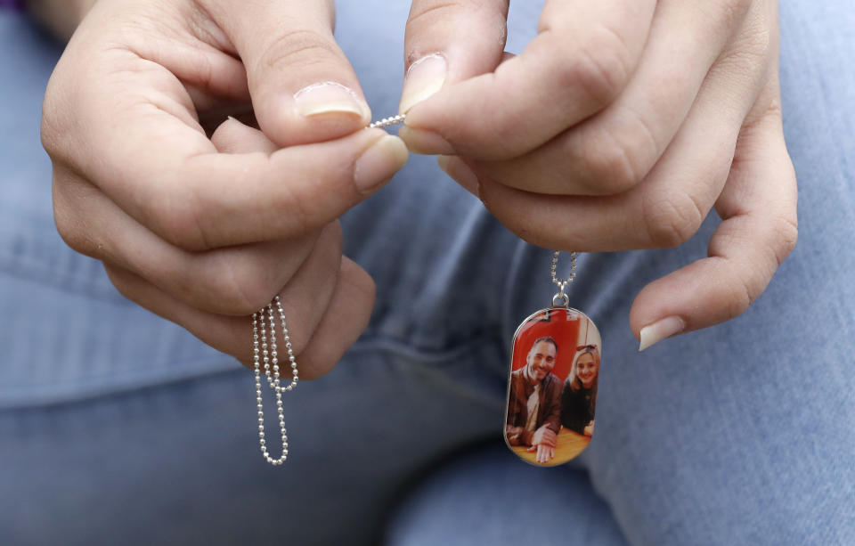 In this Tuesday, Feb. 25, 2020 photo, Aya Al-Umari, whose brother Hussein Al-Umari was killed in the Al Noor mosque shooting, holds a pendant with their photo at her home in Christchurch, New Zealand. Fifty-one people were killed and dozens more injured when a lone gunman attacked two mosques in Christchurch last year. New Zealanders on Sunday, March 15, will commemorate those who died on the first anniversary of the mass killing, as the tragedy continues to ripple through the community. Three people whose lives were forever altered that day say it has prompted changes in their career aspirations, living situations and in the way that others perceive them. (AP Photo/Mark Baker)