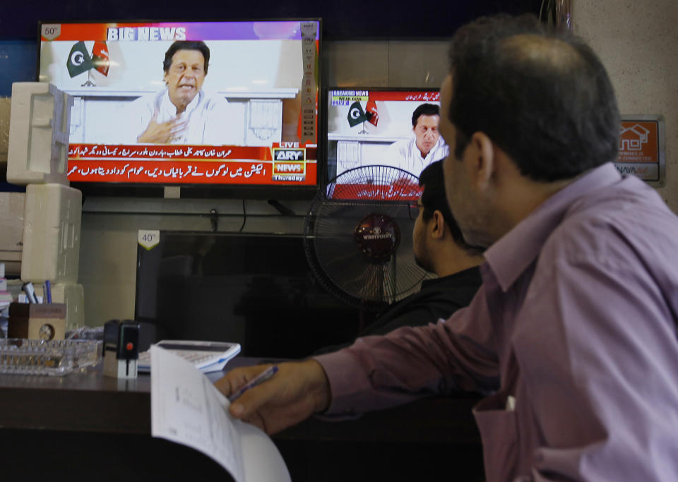 Shopkeepers listen the speech of Pakistani politician Imran Khan, chief of Pakistan Tehreek-e-Insaf party, telecasting on news channels at a shop in Islamabad, Pakistan, Thursday, July 26, 2018. Khan declared victory Thursday for his party in the country's general elections, promising a "new" Pakistan following a vote that was marred by allegations of fraud and militant violence. (AP Photo/Anjum Naveed)