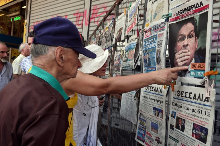 People read newspaper headlines showing the results of Greece's referendum, in Athens on July 6, 2015