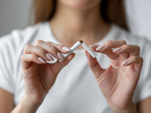 A woman in a white shirt breaking a cigarette in half