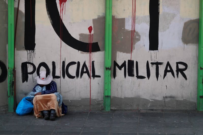 Una mujer se sienta apoyada en una pared con un grafiti que dice "policía militar" en La Paz. Noviembre 16, 2019. REUTERS/Henry Romero