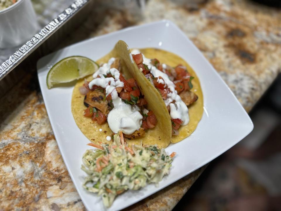 Two grilled chicken tacos with a side of coleslaw on a plate