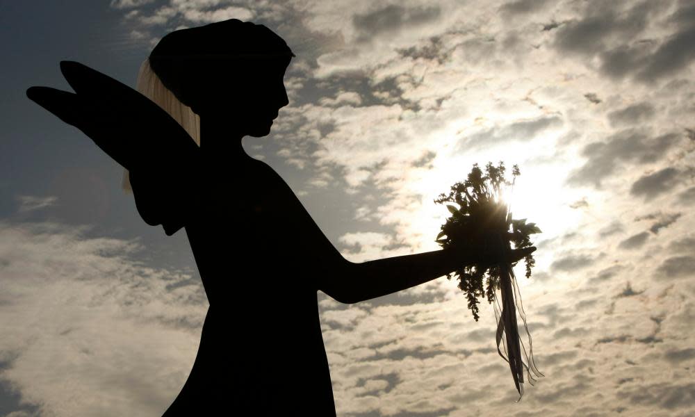 An angel sculpture is silhouetted against the setting sun