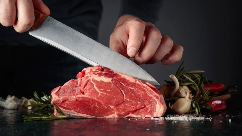 Chef thinly slicing raw meat