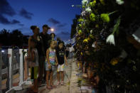 FILE - Well-wishers visit a makeshift memorial for the victims of the Champlain Towers South condo building collapse, as they gather for a multi-faith vigil near the site where the building once stood on July 15, 2021, in Surfside, Fla. Friday marks the anniversary of the oceanfront condo building collapse that killed 98 people in Surfside, Florida. The 12-story tower came down with a thunderous roar and left a giant pile of rubble in one of the deadliest collapses in U.S. history. (AP Photo/Rebecca Blackwell, File)