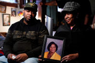 Wayne Jones, left, looks on as his aunt JoAnn Daniels, holds a photograph of his mother Celestine Chaney, who was killed in Saturday's shooting at a supermarket, during an interview with The Associated Press in Buffalo, N.Y., Monday, May 16, 2022. (AP Photo/Matt Rourke)