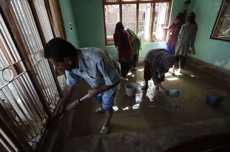 A Kashmiri family clean their house after flood waters receded from the area in Srinagar September 15, 2014. REUTERS/Adnan Abidi