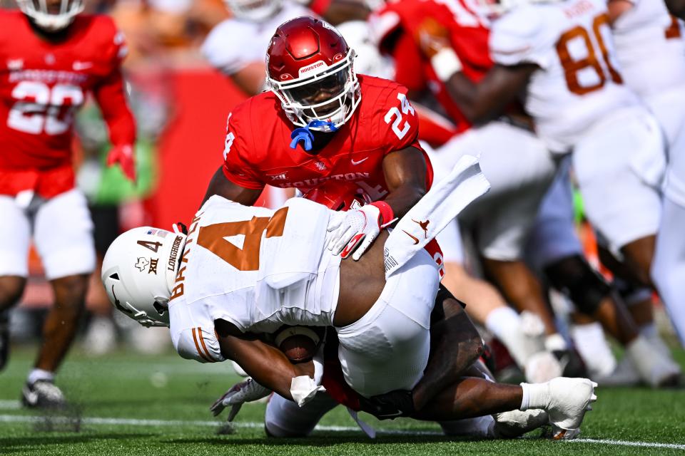 Oct 21, 2023; Houston, Texas, USA; Texas Longhorns running back CJ Baxter (4) is tackled by Houston Cougars defensive lineman Nelson Ceaser (9) during the second quarter at TDECU Stadium. Mandatory Credit: Maria Lysaker-USA TODAY Sports