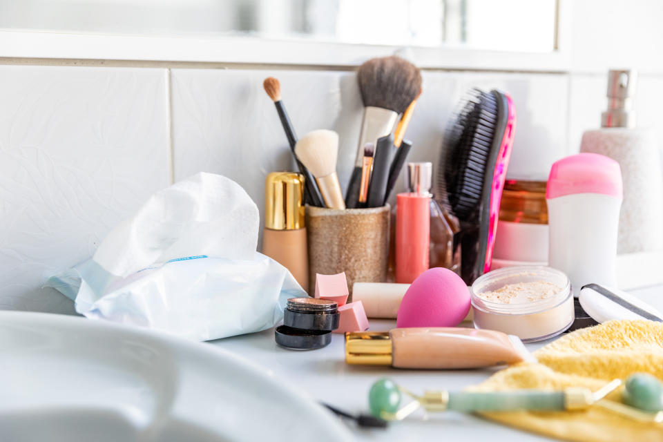 Assorted makeup products and tools spread out on a bathroom counter