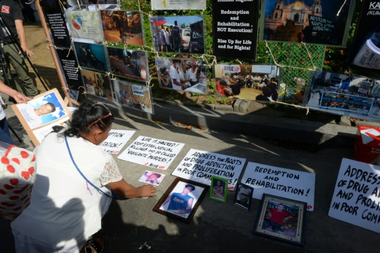 A relative of a victim of extra-judicial killings in President Rodrigo Duterte's drug war arranges photographs of victims on the grounds of a church in Manila on March 1, 2017