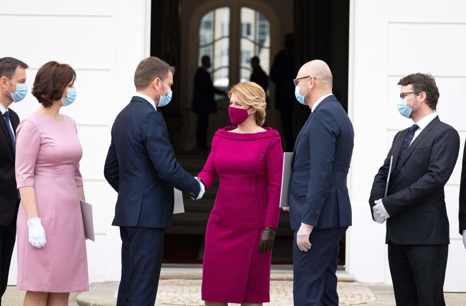 Newly appointed Slovak Prime Minister Igor Matovic (3rdL), leader of the OLaNO anti-graft party shakes hands with President Zuzana Caputova (C) after a swearing in ceremony of the new four-party coalition government on March 21, 2020 outside of the Presidential palace in Bratislava. - The ceremony was held without members of the press and all appointed government members wore gloves and face mask to prevent the spread of novel coronavirus. (Photo by JOE KLAMAR / AFP) (Photo by JOE KLAMAR/AFP via Getty Images)