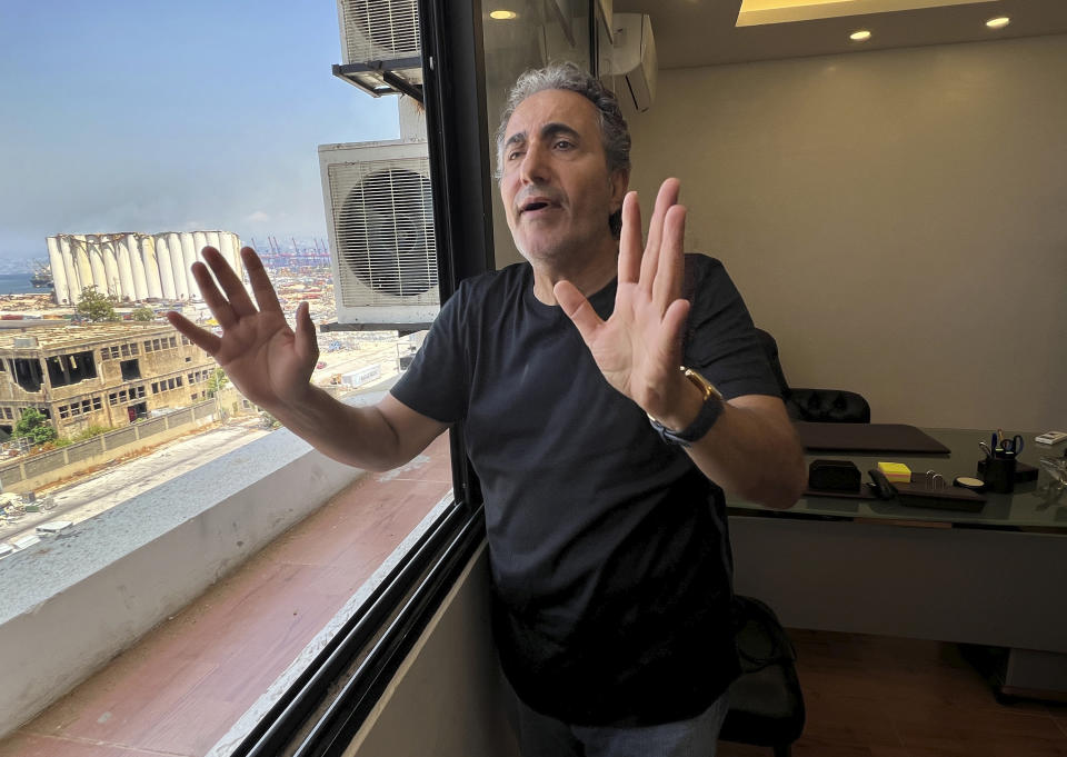 Mohammad Daife, manager of a family-run customs service company by the port, gestures during an interview with The Associated Press at his office which is close to the seaport, as the damaged silo seen in the background, in Beirut, Lebanon, Thursday, July 28, 2022. Emmanuel Durand, a French civil engineer who volunteered for the Lebanese government-commissioned team of experts says it is inevitable that the north block going to collapse. It's only just a matter of time. (AP Photo/Hussein Malla)