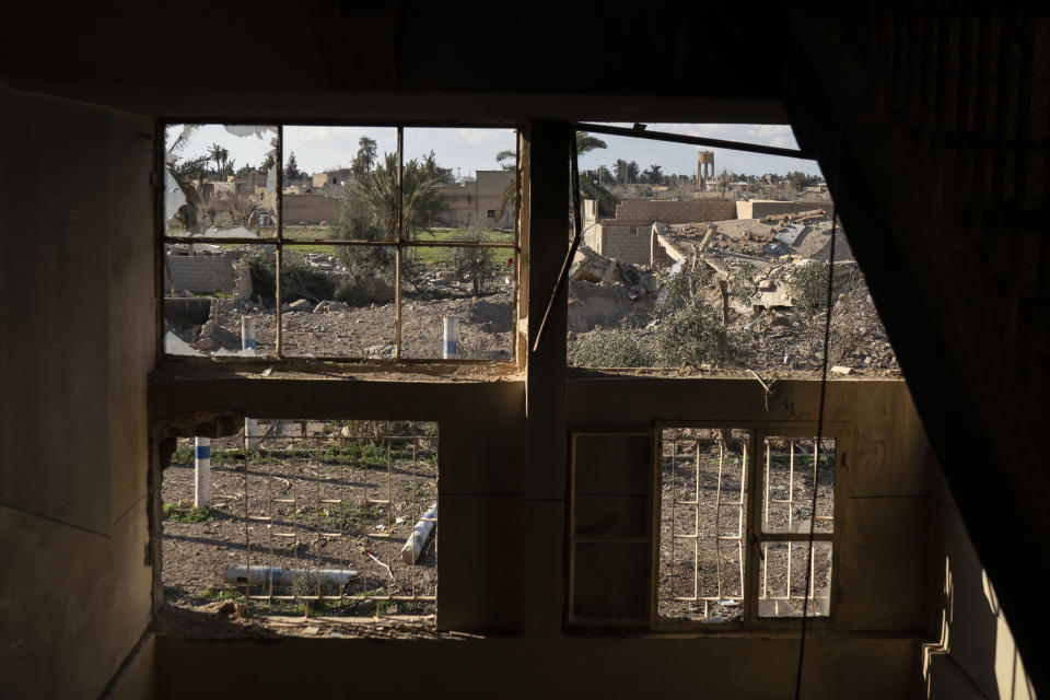 Destroyed homes are framed by damaged windows in a building taken by U.S.-backed Syrian Democratic Forces (SDF) near the last land still held by Islamic State militants in Baghouz, Syria, Monday, Feb. 18, 2019. Hundreds of Islamic State militants are surrounded in a tiny area in eastern Syria are refusing to surrender and are trying to negotiate an exit, Syrian activists and a person close to the negotiations said Monday. (AP Photo/Felipe Dana)