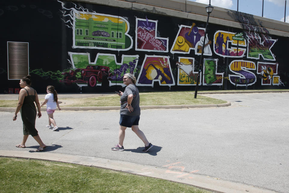 People walk past a Black Wall Street mural in the Greenwood district in Tulsa, Okla., Monday, June 15, 2020. Despite the Oklahoma heat, visitors of all races come to the site of the destroyed black community on this morning. (AP Photo/Sue Ogrocki)