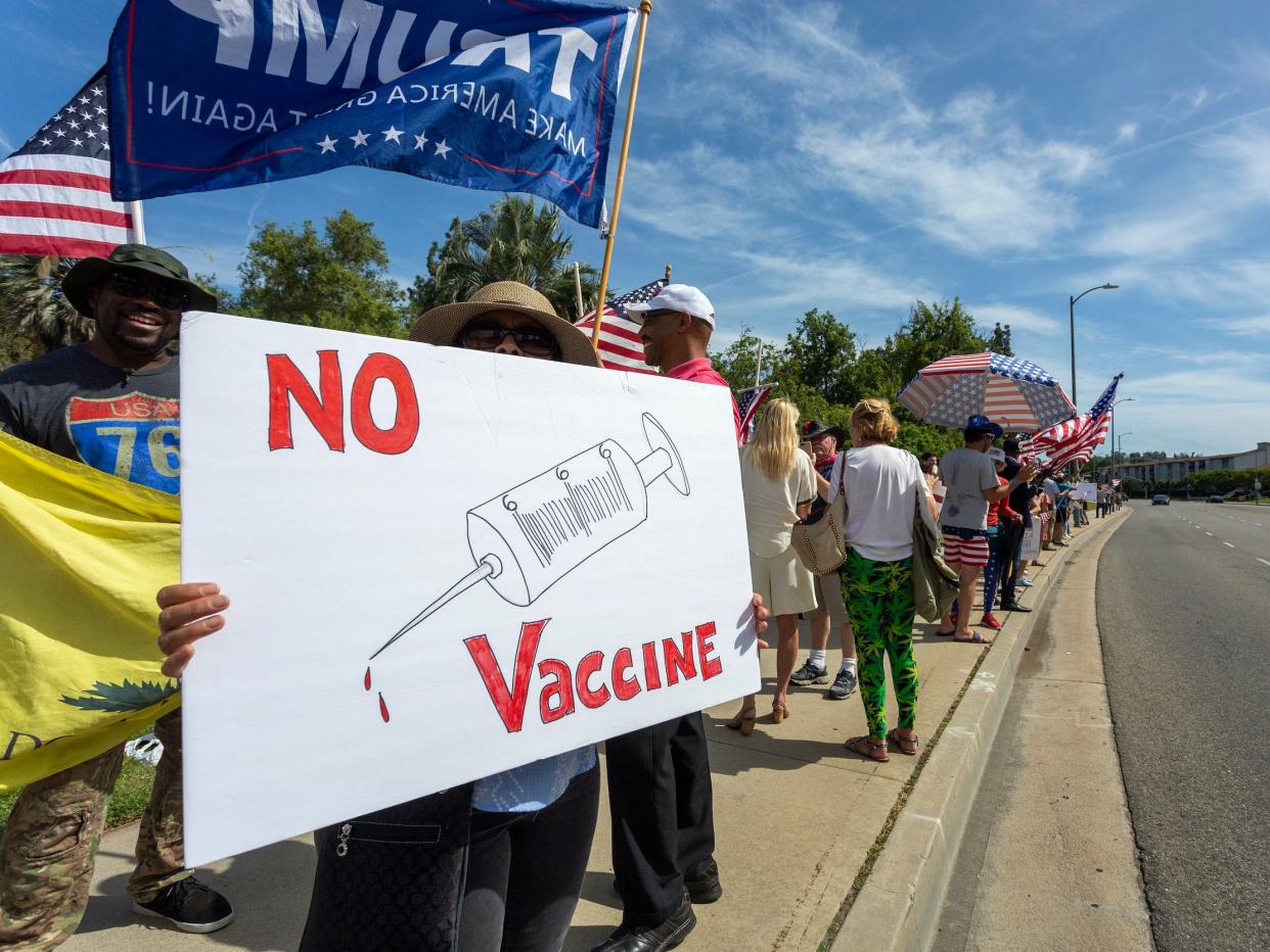 A protester holds an anti-vaccination sign as supporters of President Donald Trump rally to reopen California as the coronavirus pandemic continues to worsen, on May 16 in Woodland Hills, California.