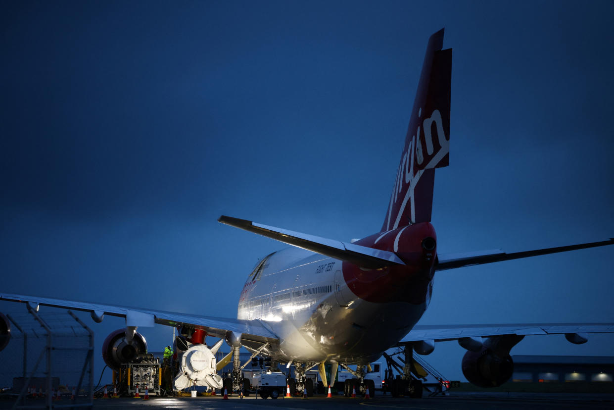 Technicians work on Virgin Orbit's LauncherOne rocket, attached to the wing of Cosmic Girl, a Boeing 747-400 aircraft, ahead of UK's First launch, at Spaceport Cornwall at Newquay Airport in Newquay, Britain, January 8, 2023. REUTERS/Henry Nicholls
