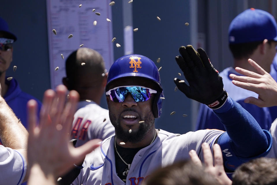 New York Mets' Starling Marte is congratulated by teammates in the dugout as sunflower seeds are thrown at him after hitting a solo home run during the third inning of a baseball game against the Los Angeles Dodgers Sunday, June 5, 2022, in Los Angeles. (AP Photo/Mark J. Terrill)