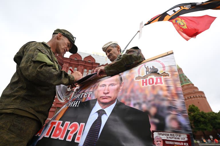 Militares rusos sostienen un retrato del presidente Putin cerca de la Plaza Roja en Moscú
