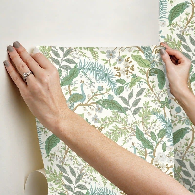 A person applying the peel and stick wallpaper