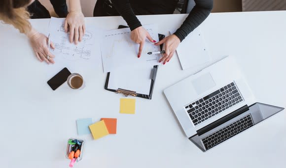 An overhead view of two people working together at a desk.