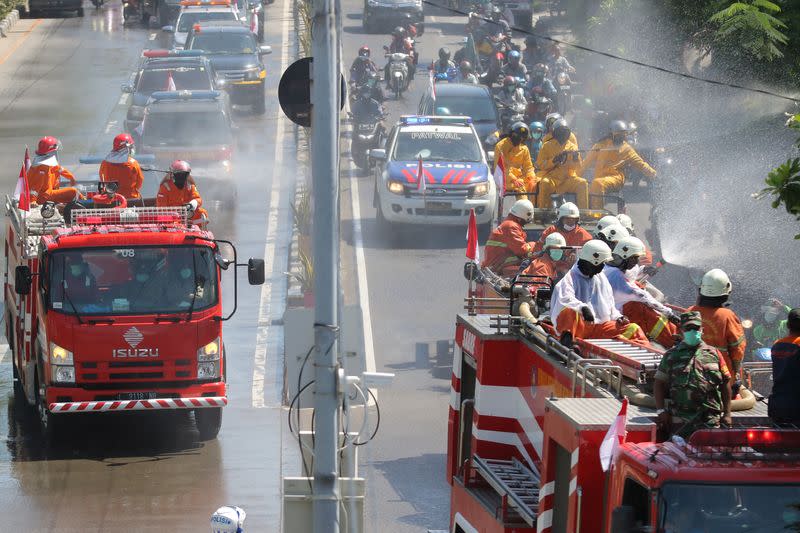 Officers spray disinfectant on a road to prevent the spread of coronavirus disease (COVID-19) in Surabaya