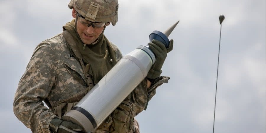 A US soldier holds a 120mm M829A4 depleted uranium tank projectile