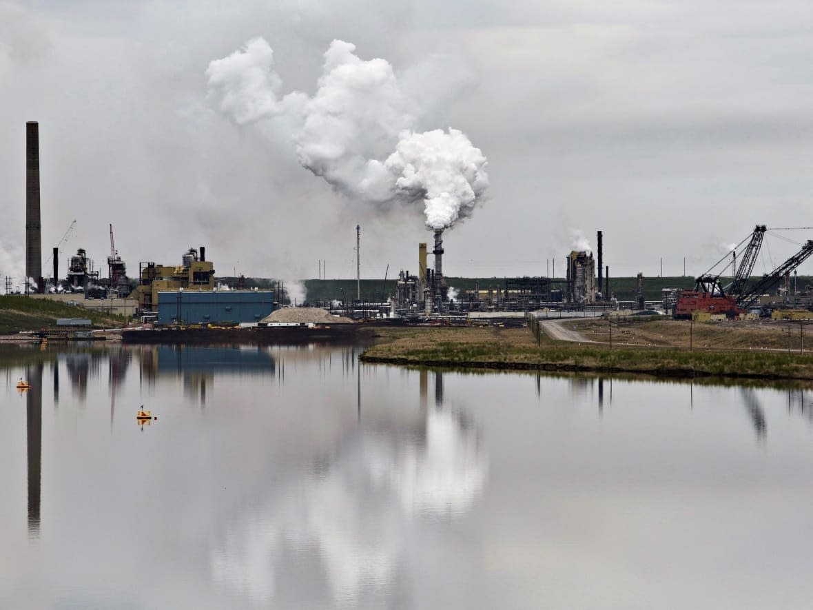 An oil sands extraction facility is reflected in a tailings pond near the city of Fort McMurray, Alberta on June 1, 2014. (Jason Franson/The Canadian Press - image credit)