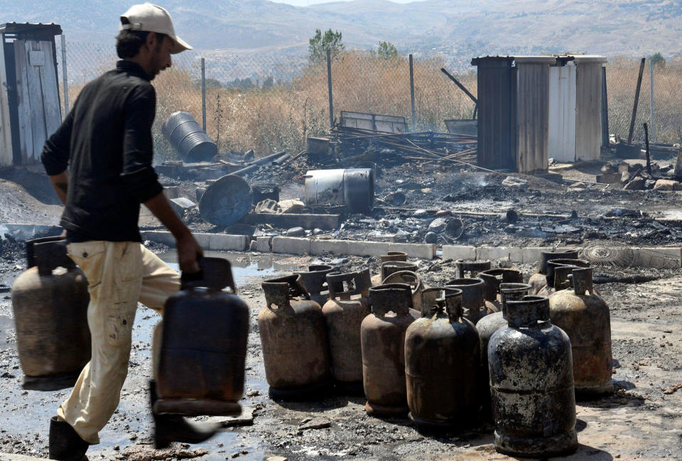 <p>A man moves gas canisters after a fire tore through a camp for Syrian refugees, near the town of Qab Elias, in Lebanon’s Bekaa Valley, July 2, 2017. (Hassan Abdallah/Reuters) </p>