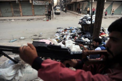 Fighters from the Syrian opposition guard a checkpoint during clashes with forces loyal to President Bashar al-Assad