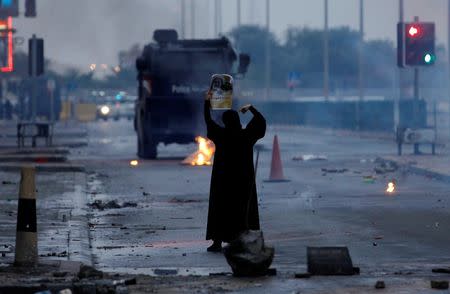 FILE PHOTO: A female protester holds a photo of Shi'ite scholar Isa Qassim as she confronts riot police armoured personnel carrier during a demonstration to mark the 6th anniversary of the February 14 uprising, in the village of Sitra, south of Manama, Bahrain February 14, 2017. REUTERS/Hamad I Mohammed/File Photo