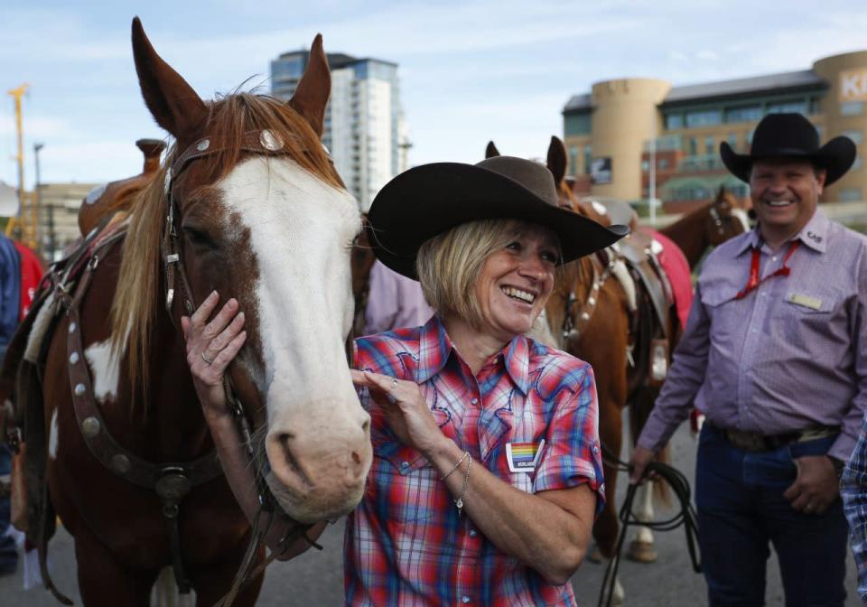 Alberta premier Rachel Notley pets a horse before the start of the Calgary Stampede parade in Calgary, Friday, July 8, 2016. THE CANADIAN PRESS/Jeff McIntosh