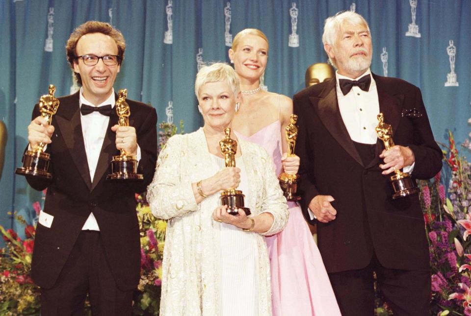 judi dench holding her oscar trophy amid a group of other winners