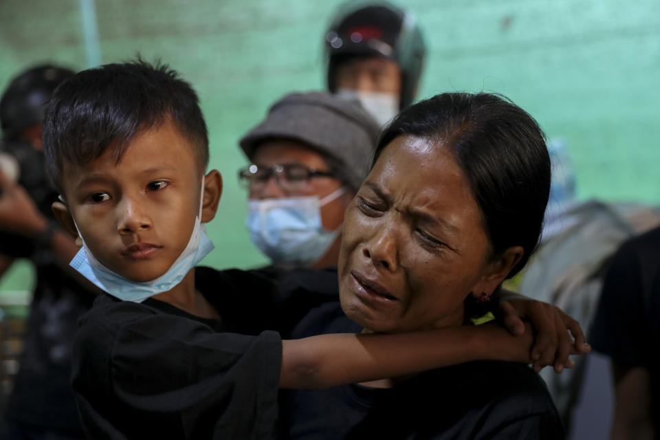 Thida Hnin, right, wife of Thet Naing Win, weeps as her son Aung Phone Khant, left, watches his father's coffin laid in their home in Mandalay, Myanmar, Tuesday, Feb. 23, 2021. Thet Naing Win was shot and killed by Myanmar security forces during an anti-coup protest on Saturday, Feb. 20. (AP Photo)