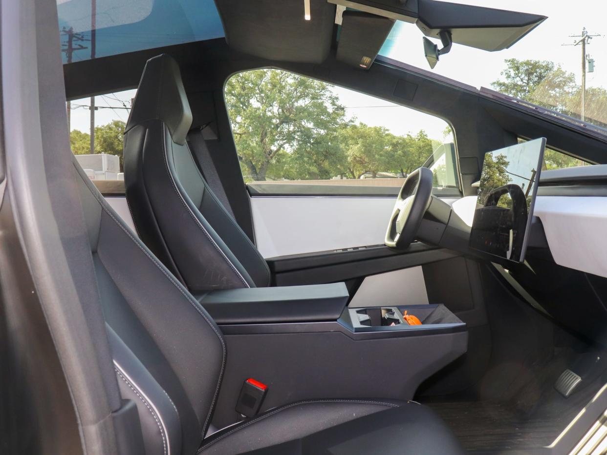 Cybertruck interior showing the driver cockpit, steering wheel, and central control screen.