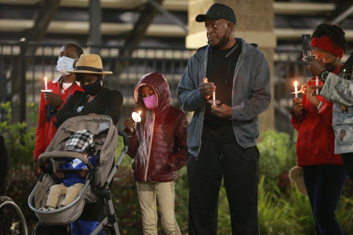A family holds candles during a Stop the Gun Violence rally on Tuesday evening at Memorial Stadium.