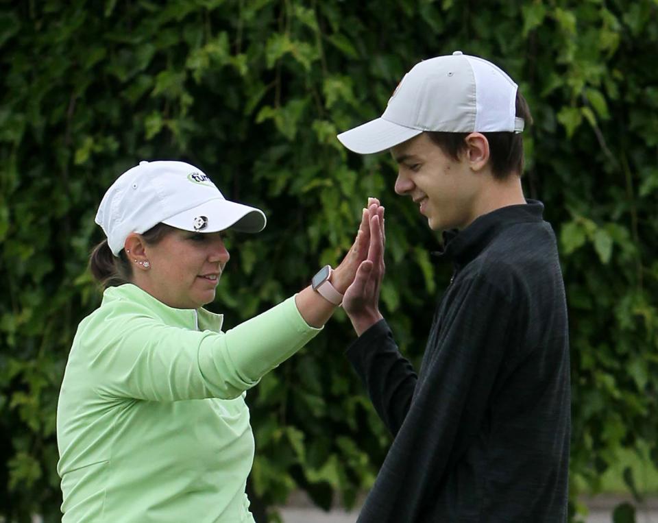 Huston Nagy, 16, of North Olmsted, right, gets a high-five from his coach Erin Craig after sinking a putt on the putting green at Firestone Country Club on Monday in Akron.