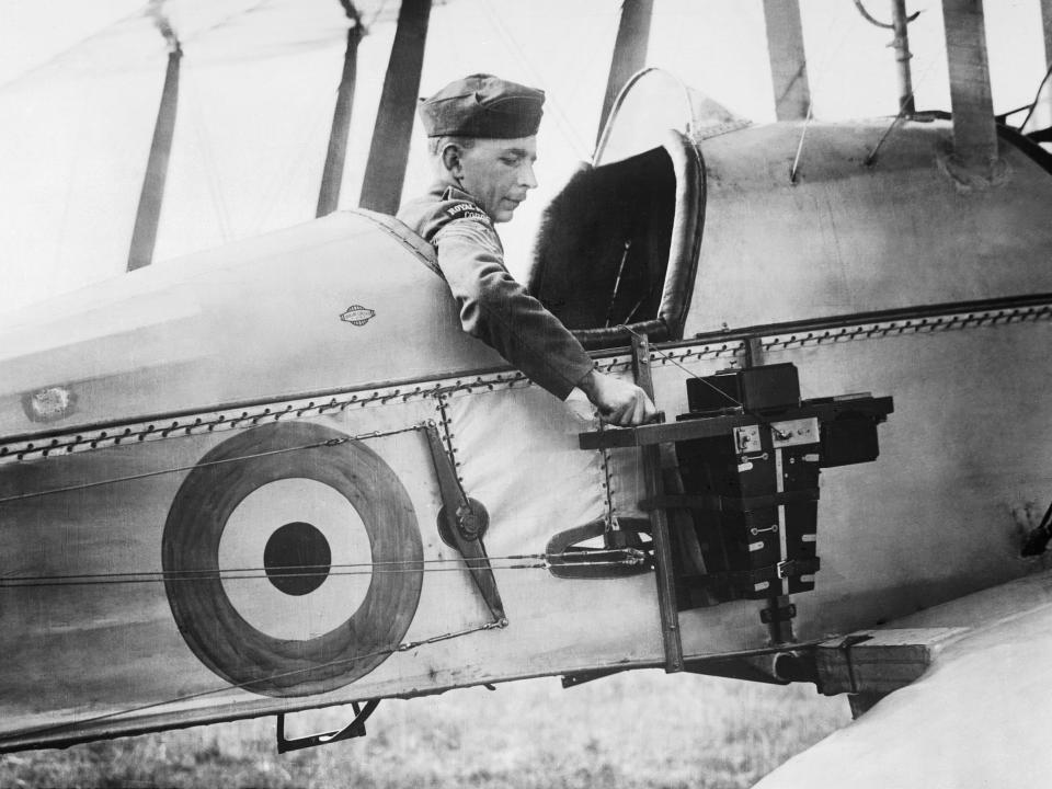 A sergeant of the Royal Flying Corps demonstrates a C type aerial reconnaissance camera fixed to the fuselage of a BE2c aircraft, 1916.