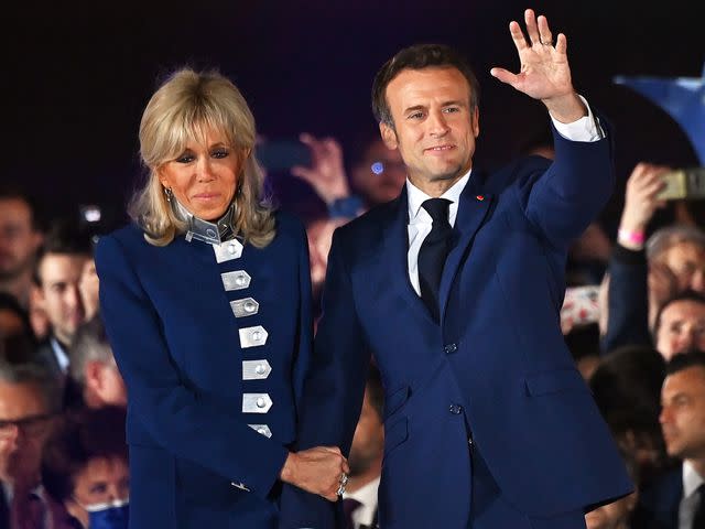 <p>Aurelien Meunier/Getty</p> Emmanuel Macron and Brigitte Macron in front of the Eiffel Tower after after giving a speech after beating his far-right rival Marine Le Pen for a second five-year term as president on April 24, 2022.